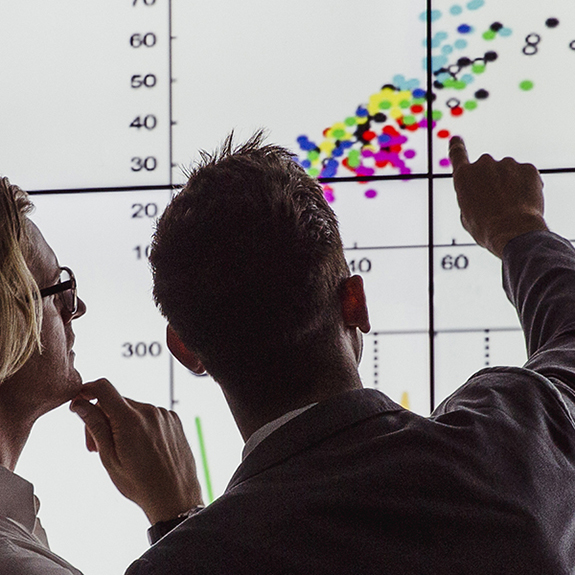 Two men standing in front of a data visualization dashboard
