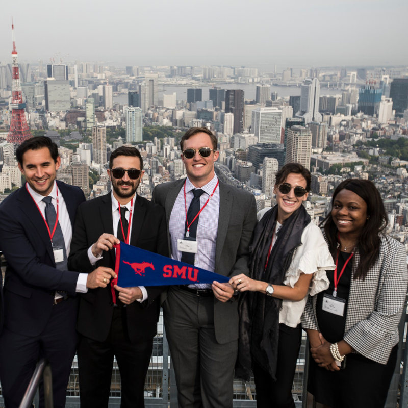 Students holding an SMU Cox flag in Tokyo