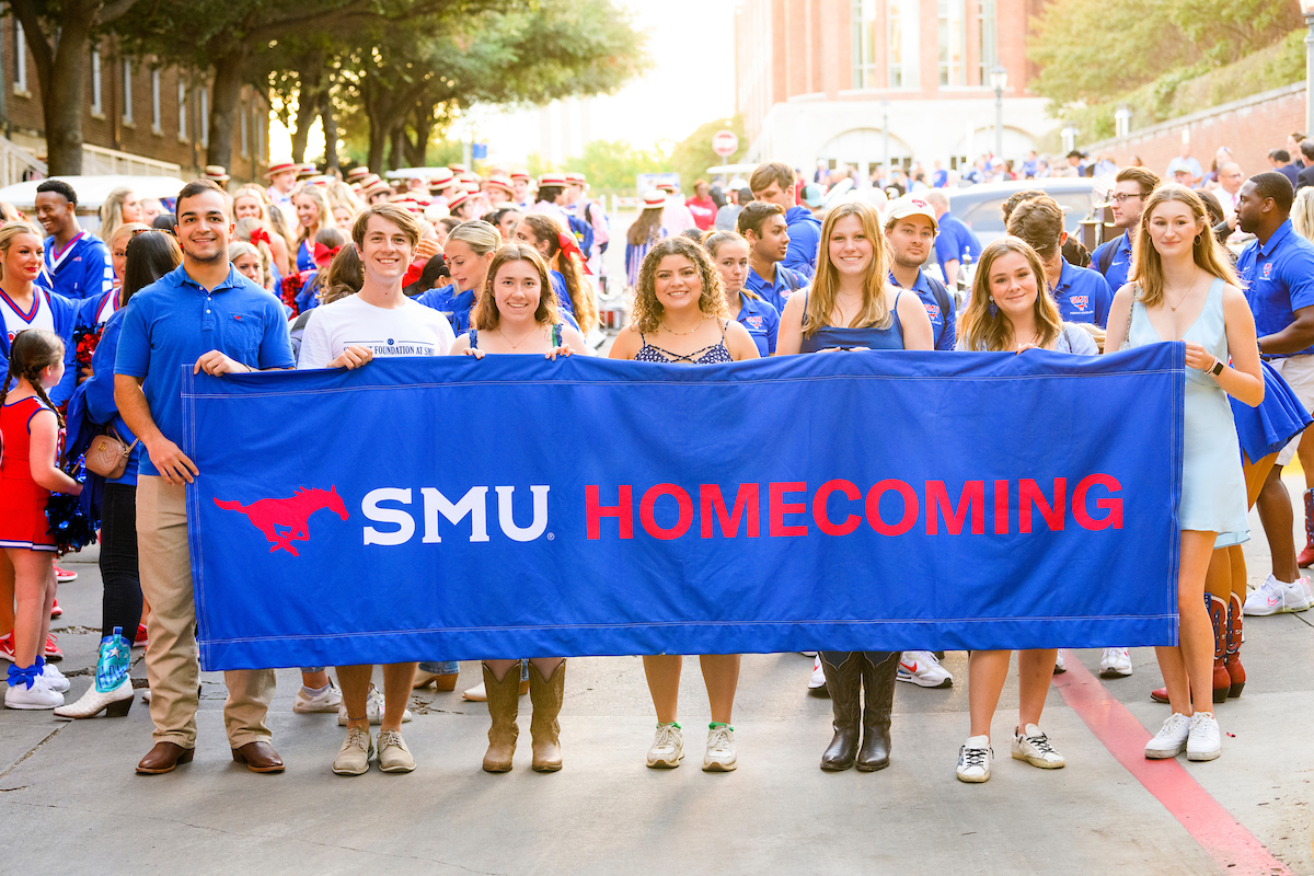 People holding up a large banner that reads SMU homecoming