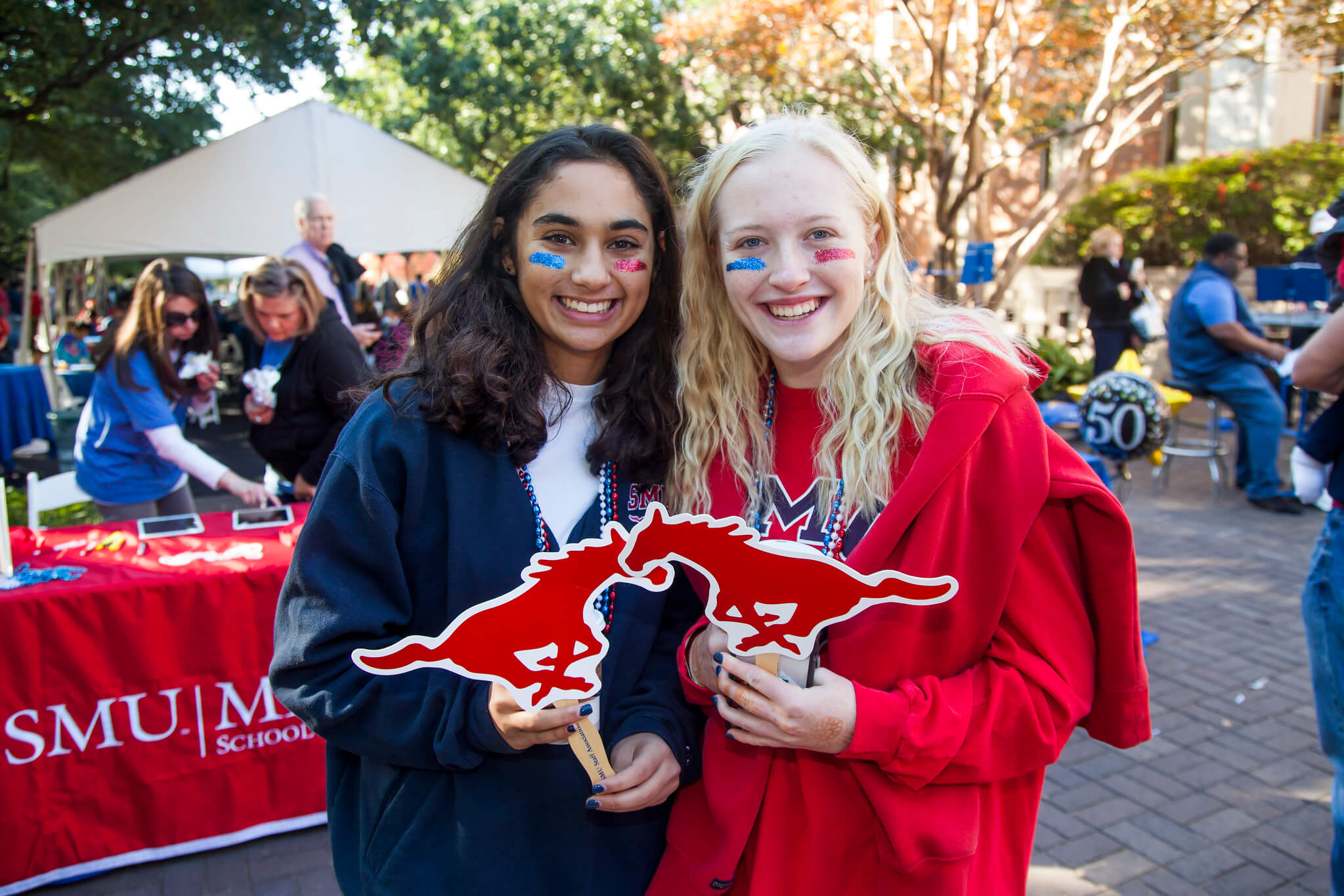 Two Meadows students smile and pose with Mustang signs at an SMU event.