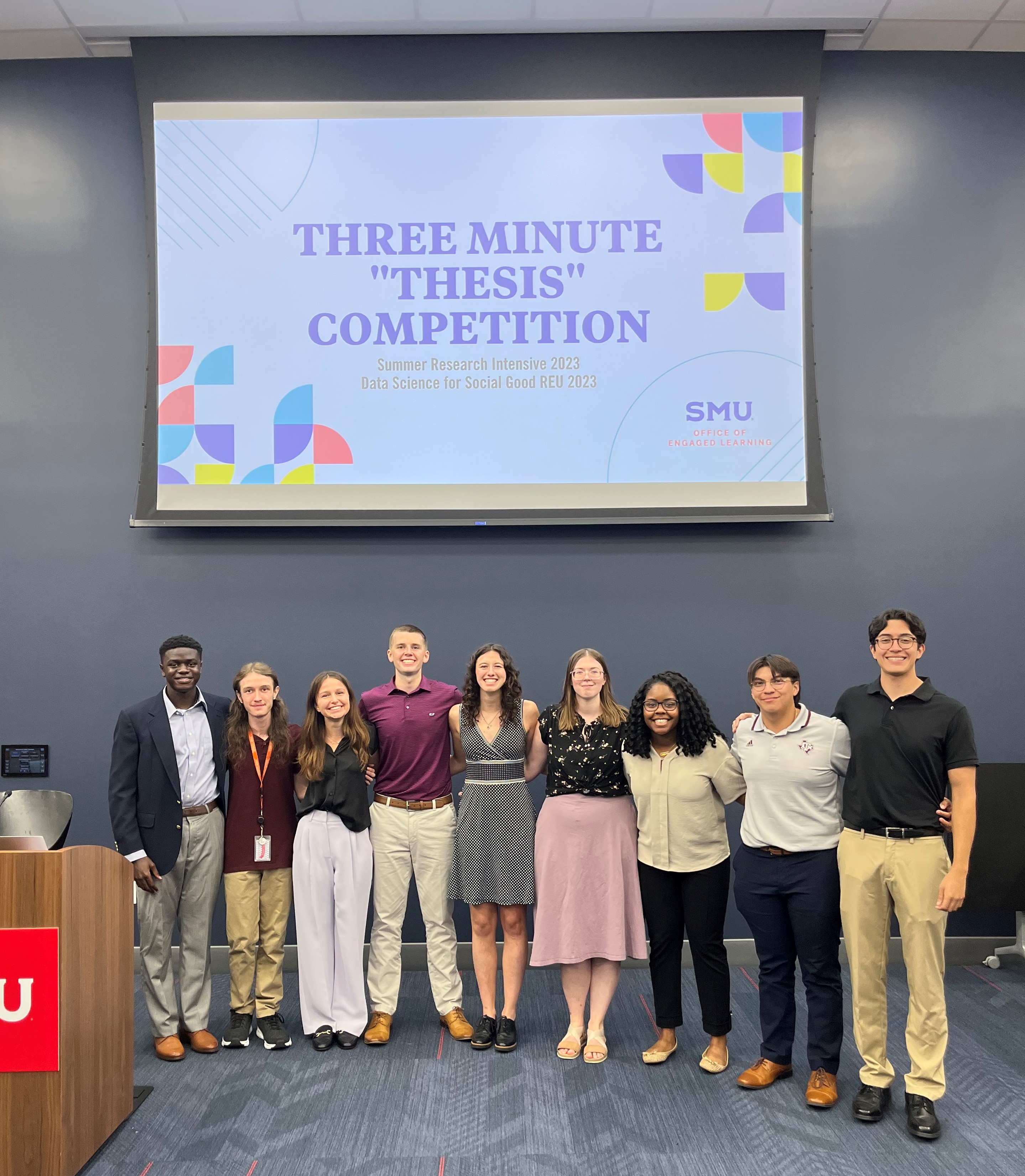 SMU REU students in front of a Three-Minute Thesis sign