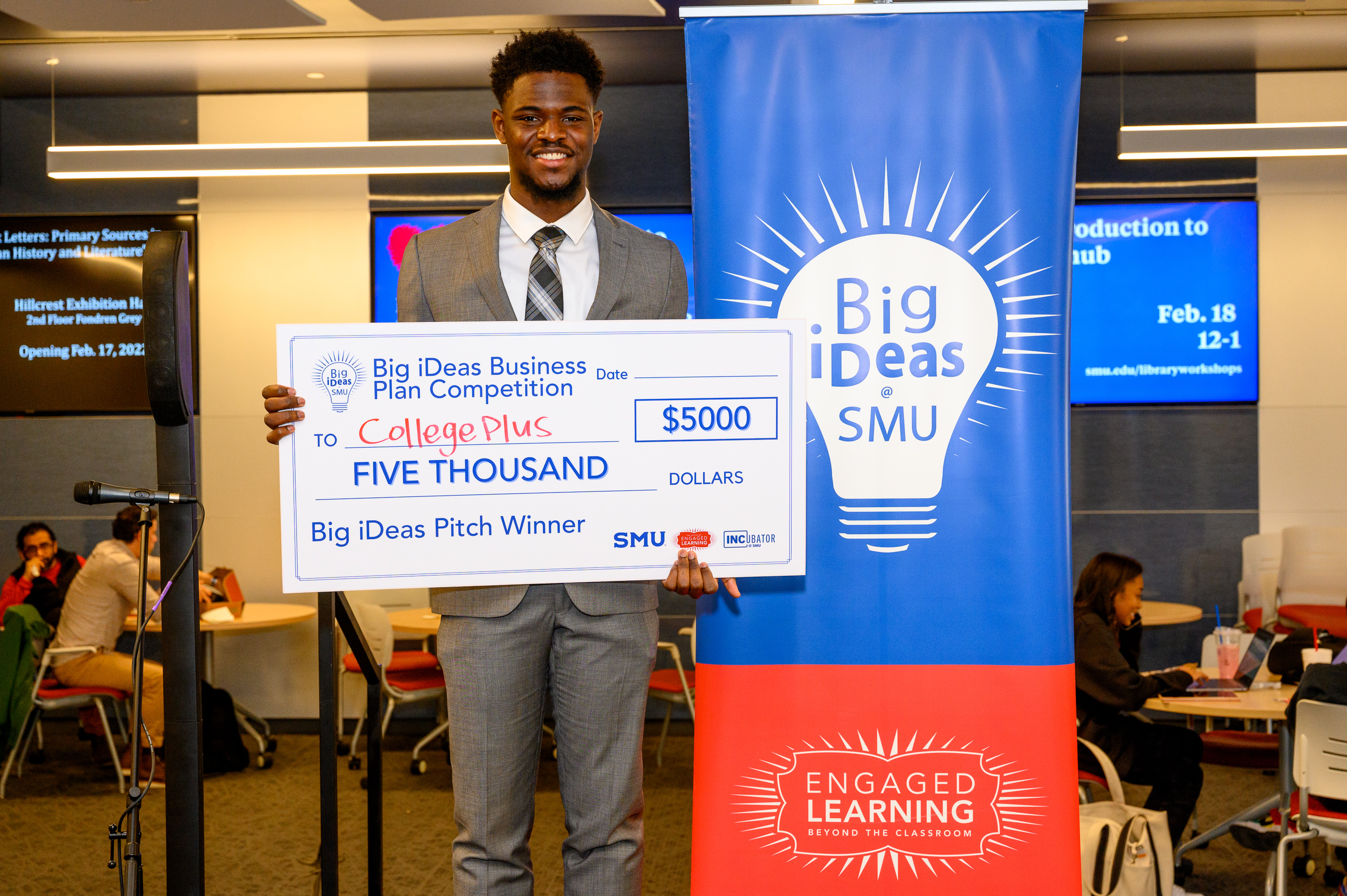 Student posing for Big ideas with a large check