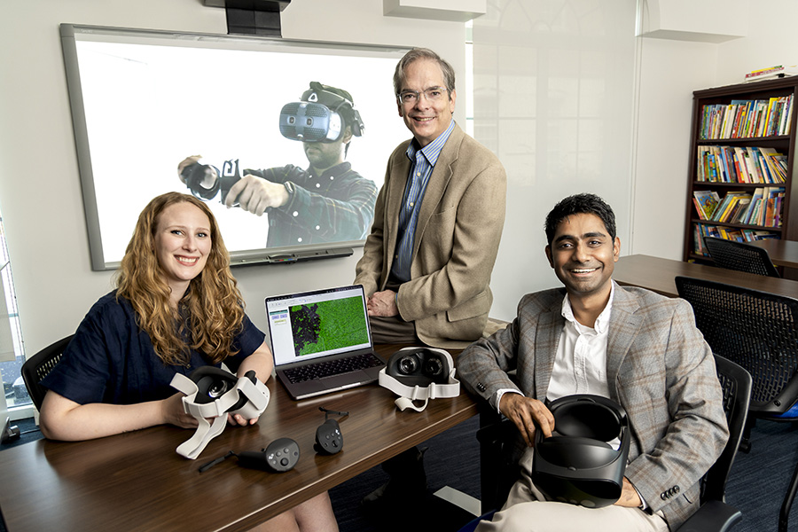 Professors Kelsey Schenck, Corey Brady, and Prajakt Pande sitting with in Mixed Realing lab with VR Equipment.