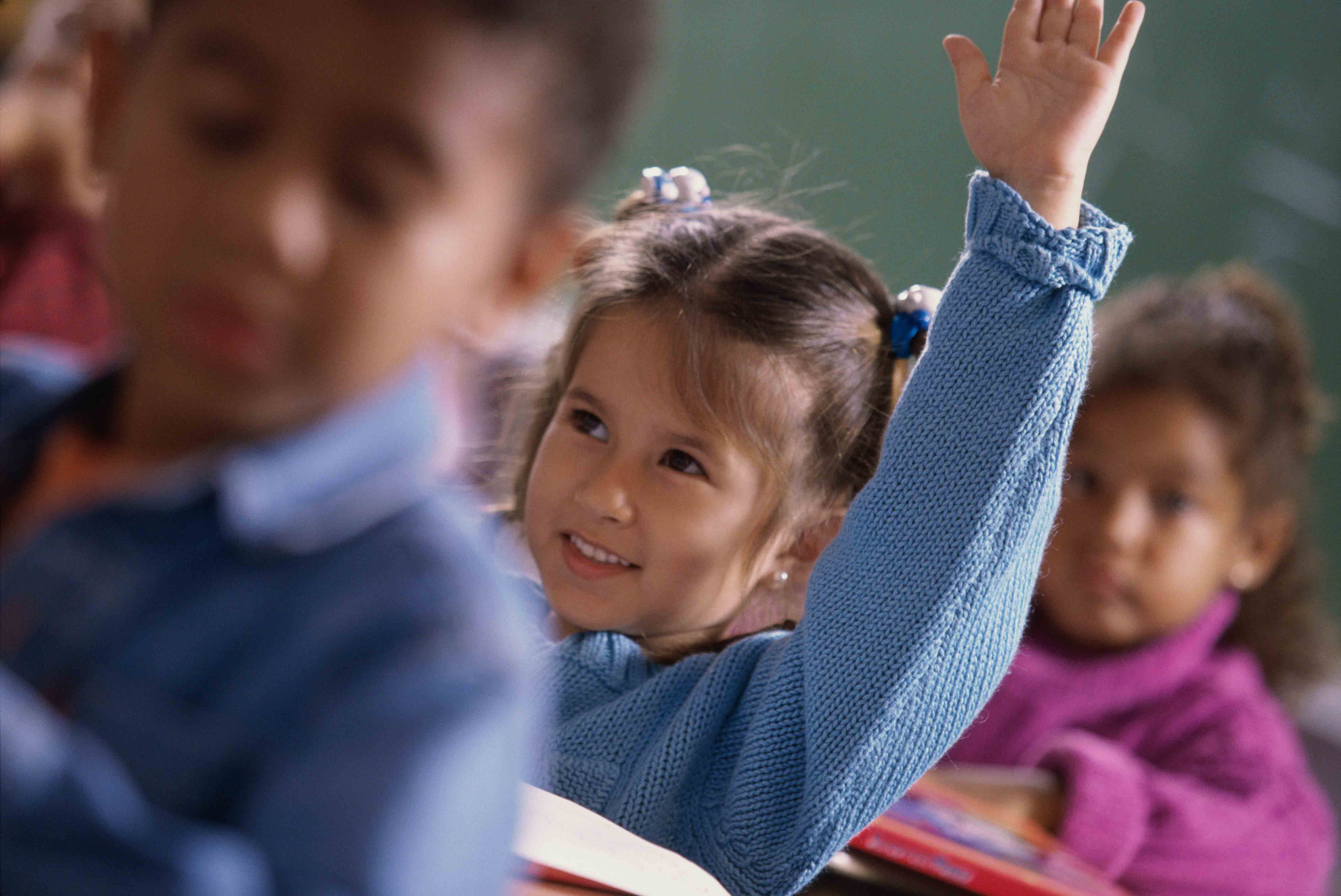 Young girl raising her hand in classroom