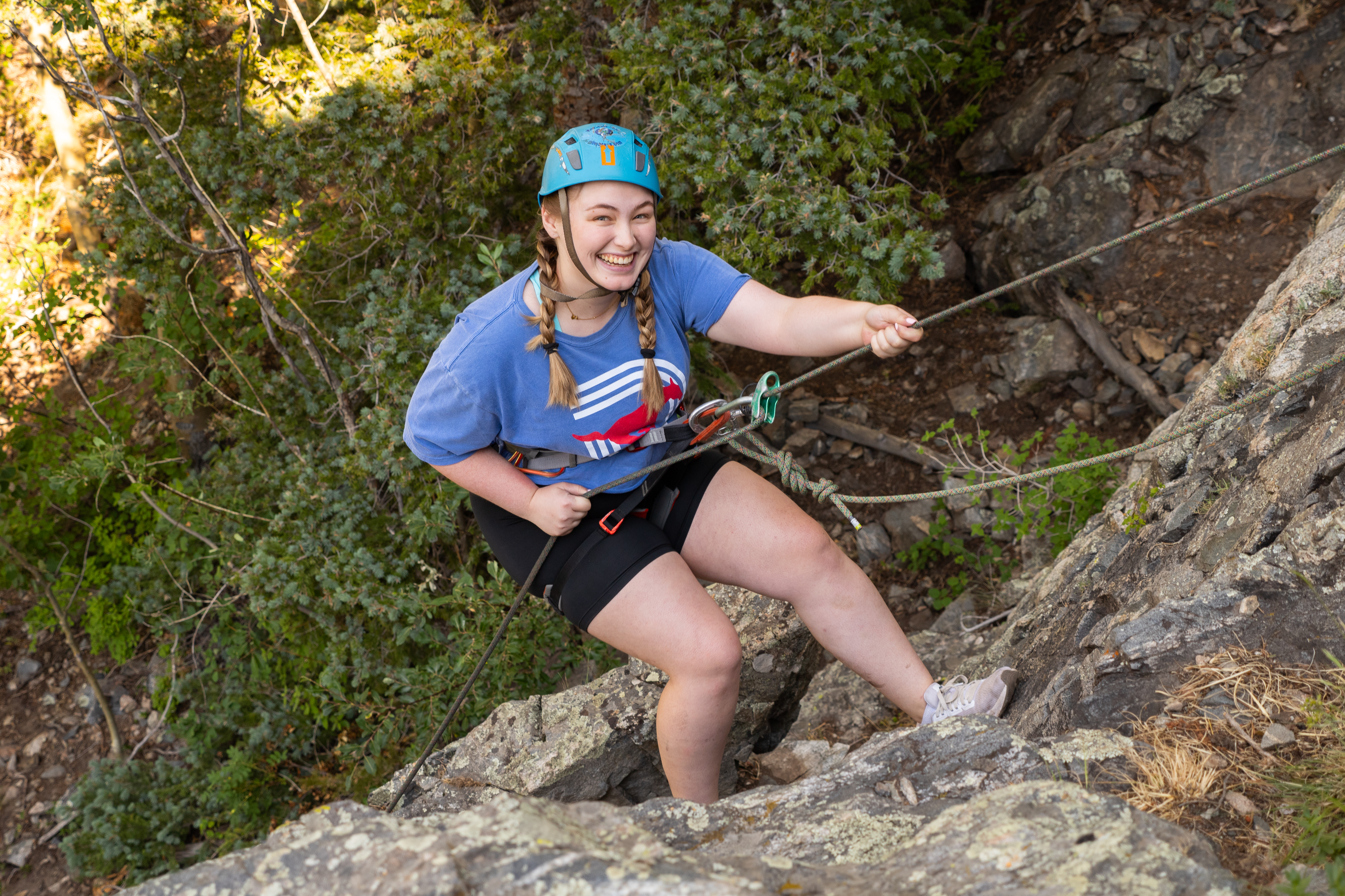 Girl in SMU Shirt Rock Climbing Looking up at camera 