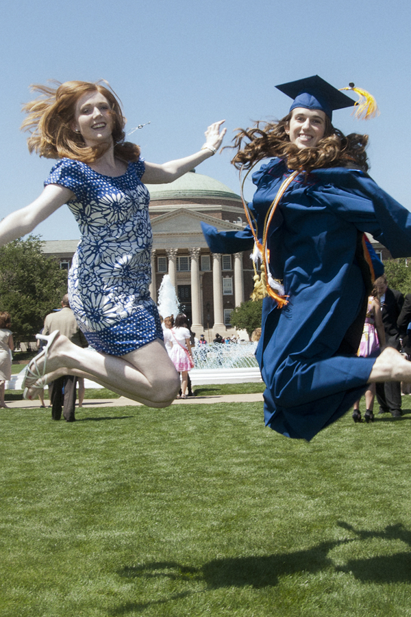 Photo (detail) showing two graduates jumping in Front of Dallas Hall