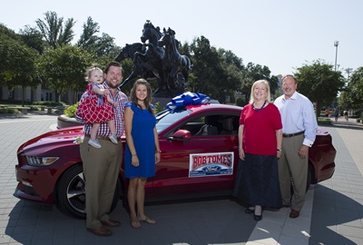Brandon Tomes ’07 with Everly Tomes, Stephanie Tomes, Barbara Utter Thomas ’78 and Bob Tomes with red Ford Mustang