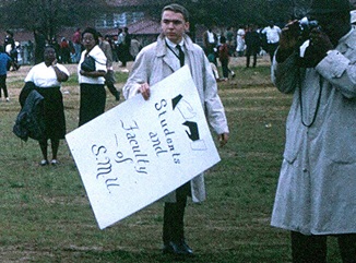SMU faculty member with a sign "Students and Faculty of SMU"
