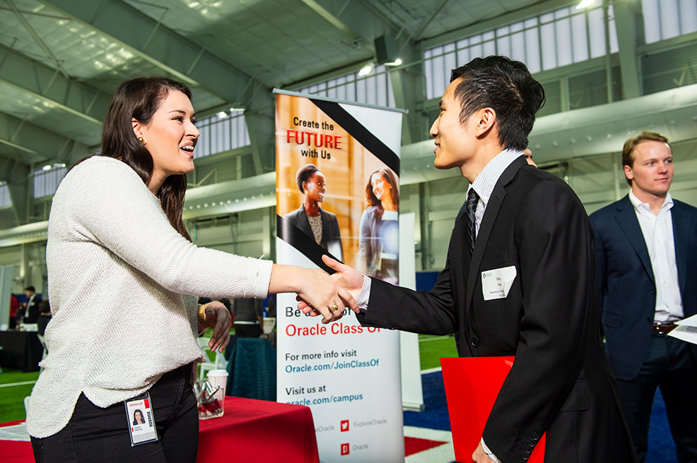 Two people shaking hands at a career fair.