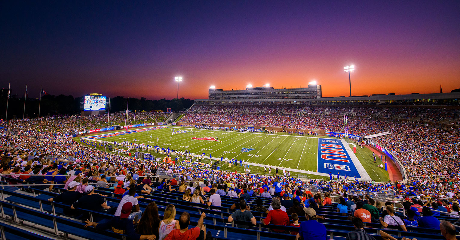 Night time shot of a large crowd attending an SMU Mustang's football game.