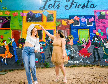 dancing in front of a Let's Fiesta mural