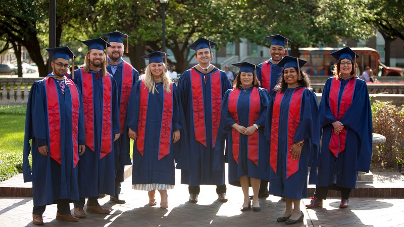 Students of the inaugural SMU Cox Online MBA Cohort in graduation caps and gowns