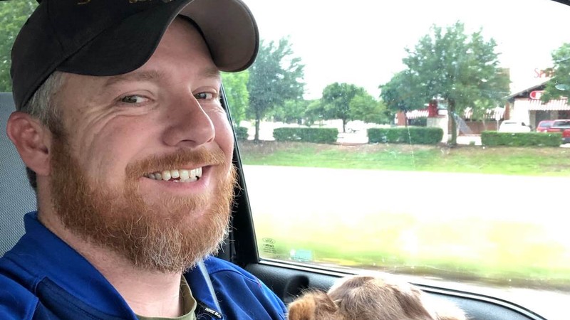Joe Best, an SMU Cox online MBA student smiles in his car with his dog