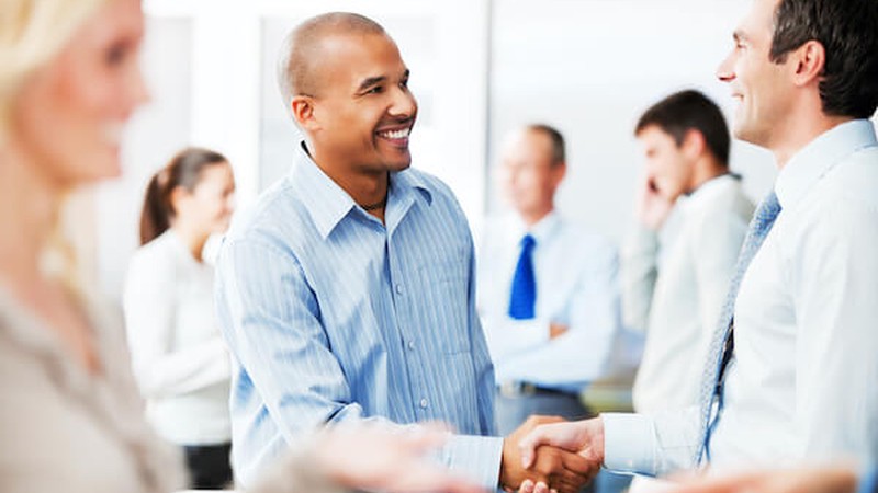 A SMU Cox online MBA student shakes hands with another business professional to network
