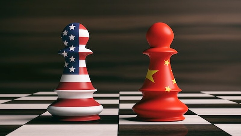 Two chess pieces with the United States and Chinese flags sit on a chess board depicting the trade war