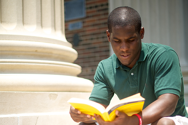 Student reading book on steps of Dallas Hall.