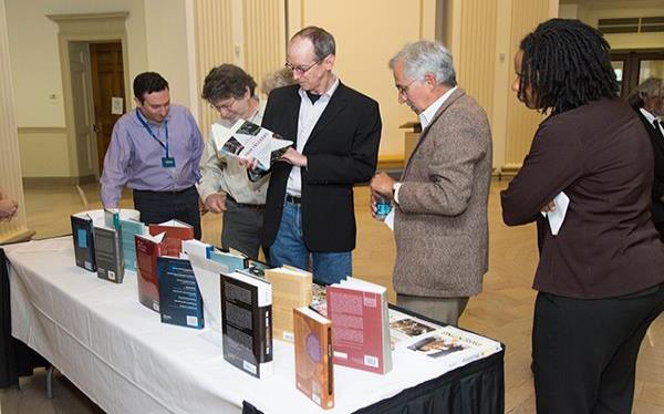 Group of people looking at books on a table. 