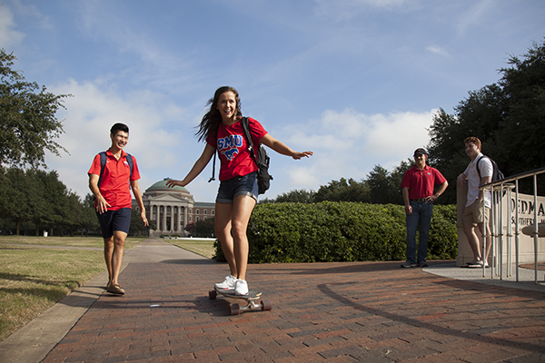 One student skateboarding while three others watch. 