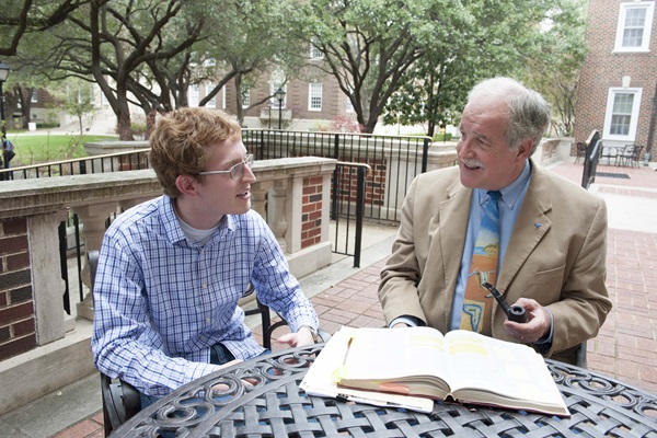 Professor and student talking at a table outside.