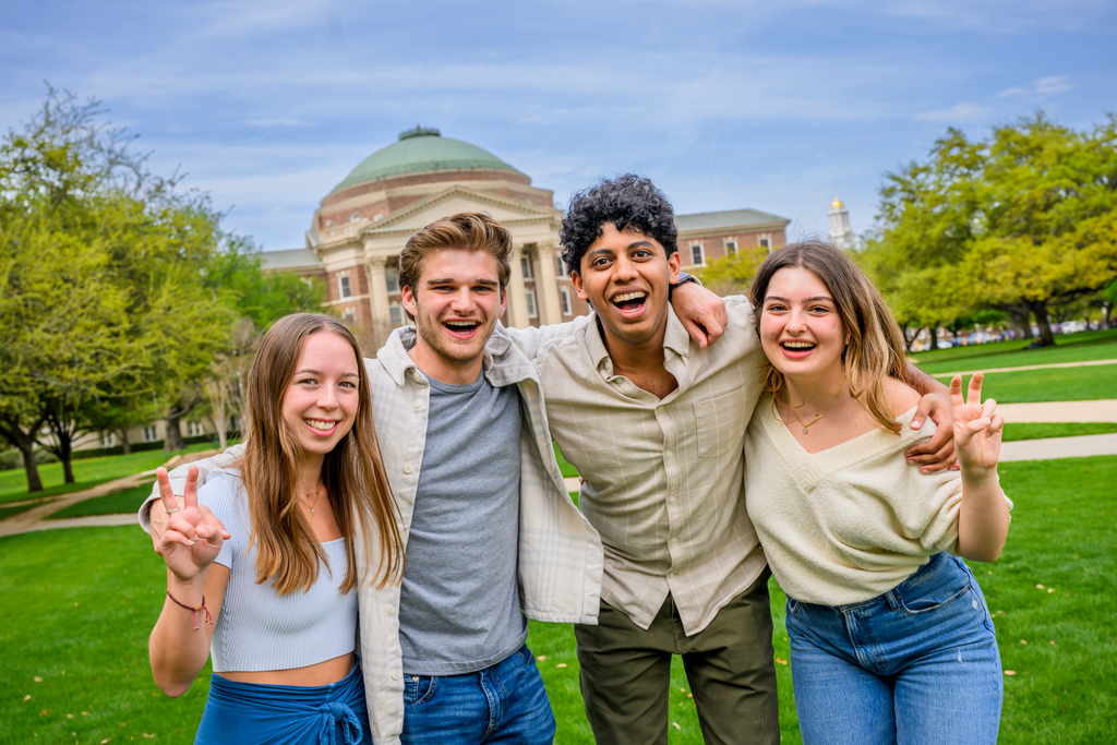 four students outside smiling