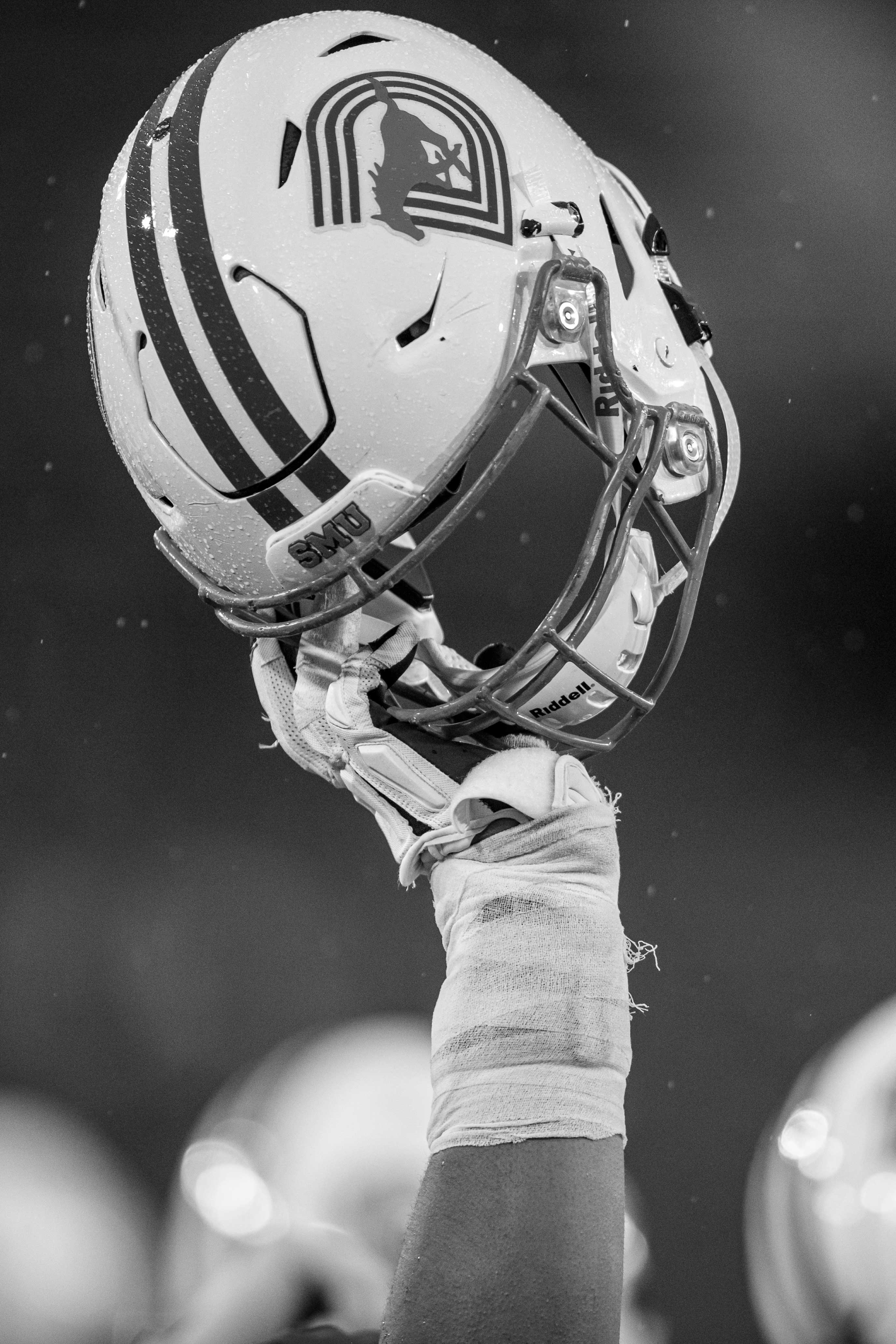 Image of football player's hand holding up a SMU Mustangs helmet