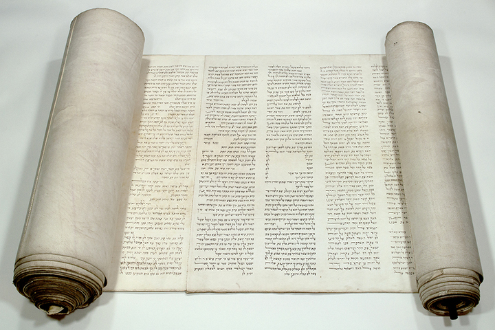 A partially opened Torah scroll with text in Hebrew.