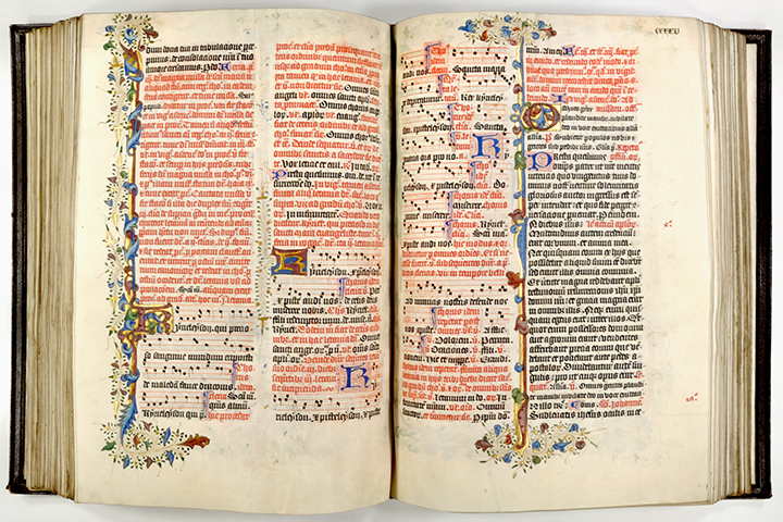 An open liturgical book, Missal, with text in Latin and musical notations. The pages have decoration including borders and initials.
