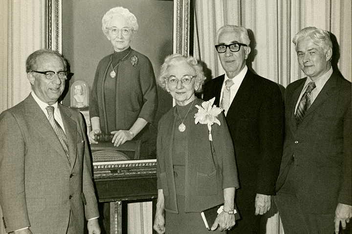 Photograph of Kate Warnick standing by her portrait with Rabbi Olan, Bishop Slater, and Dean Quillian.