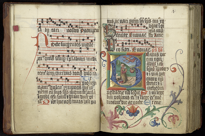 An open Latin song book, with musical notation, decorated borders, and an illuminated image of King David introducing the first psalm.