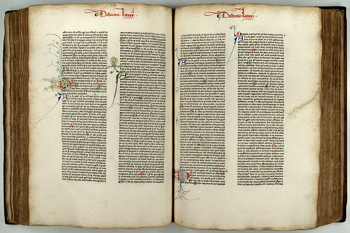 Open book with the Latin text of Saint Augustine's Summa theologicae with colorful handwritten initials.