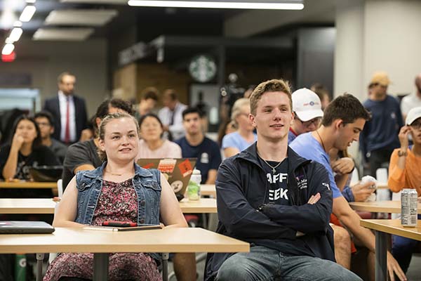 two students sit in crowded Collaborative Commons event