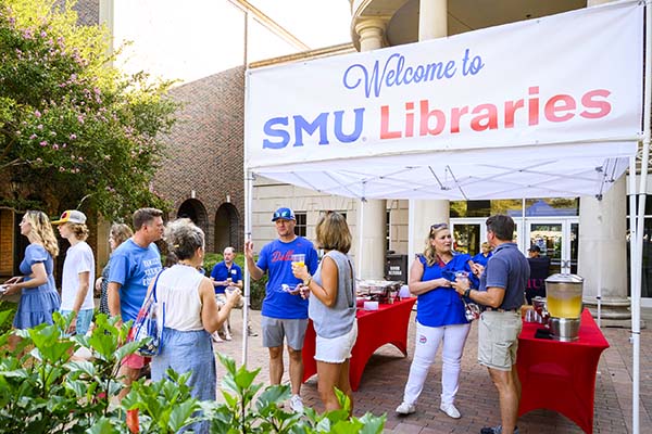 SMU community members standing under a sign that reads Welcome to SMU Libraries at an event outside Fondren Library