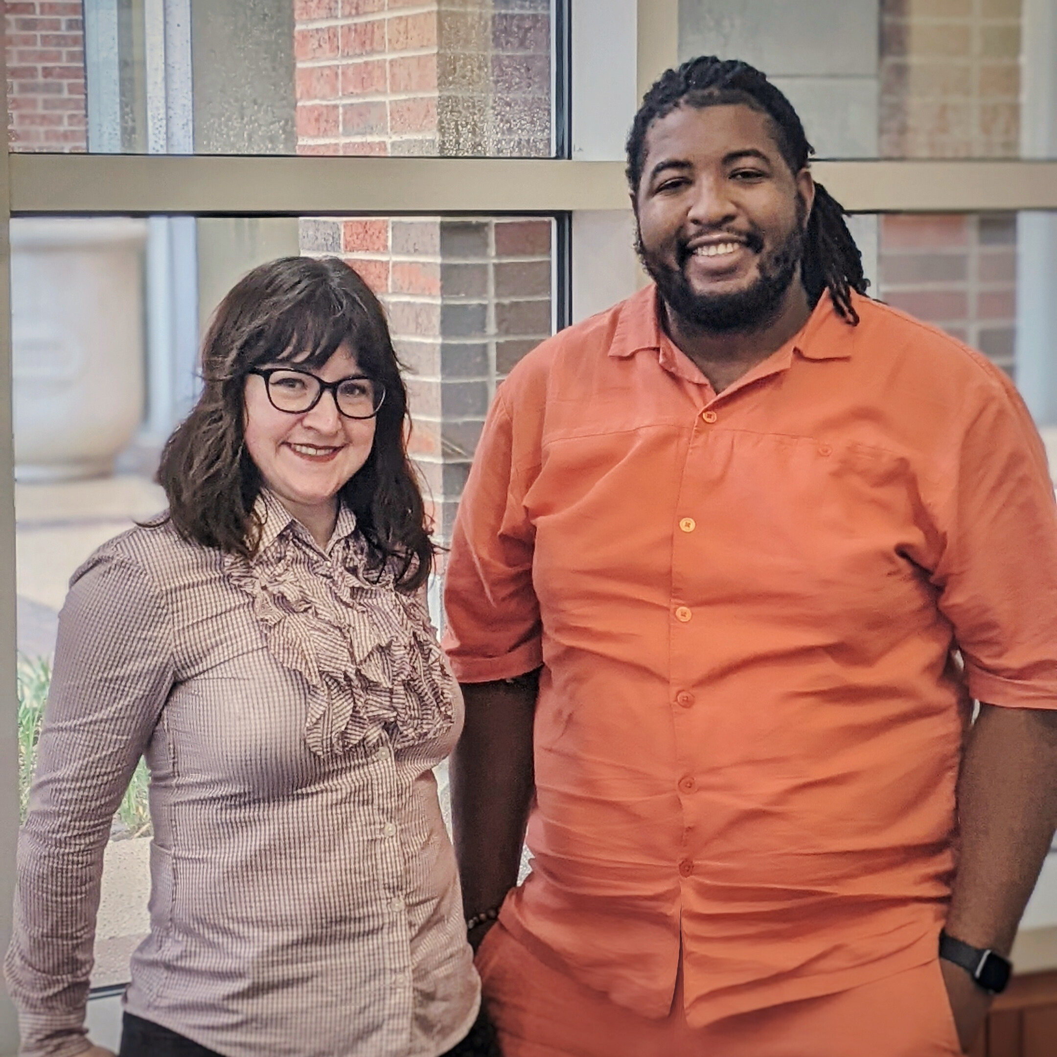 Student workers Joy Morrow and Azeez Akande posing in Hamon Arts Library. Both are smiling.