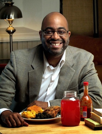 Adrian Miller smiling in front of a plate of food