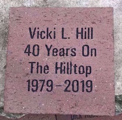 Square paver with four lines of text reading Vicki L. Hill 40 Years On The Hilltop 1979-2019