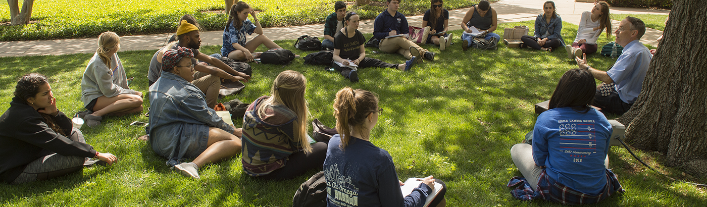 students sitting on lawn listening to professor