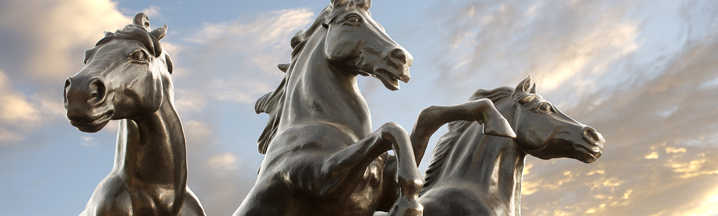 sculpture of three horses at sunset