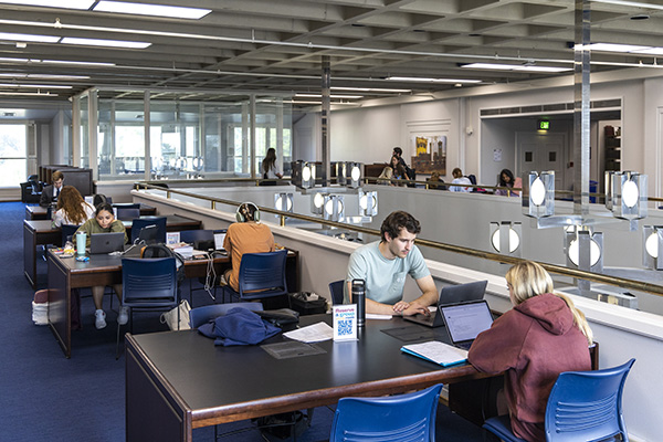 Students studying at tables around the third floor of the law library