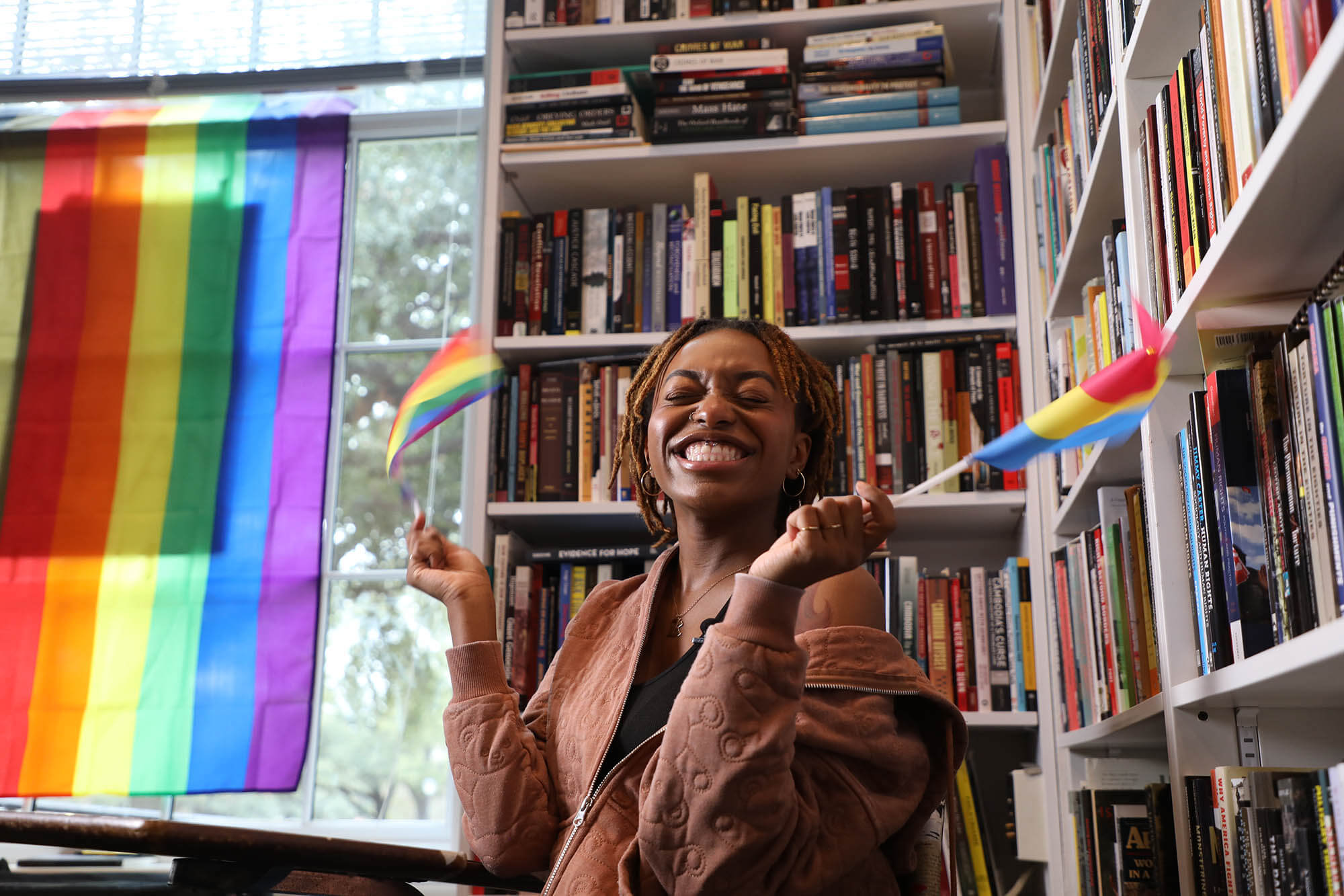 Black woman in library with LGTBQIA+ flag