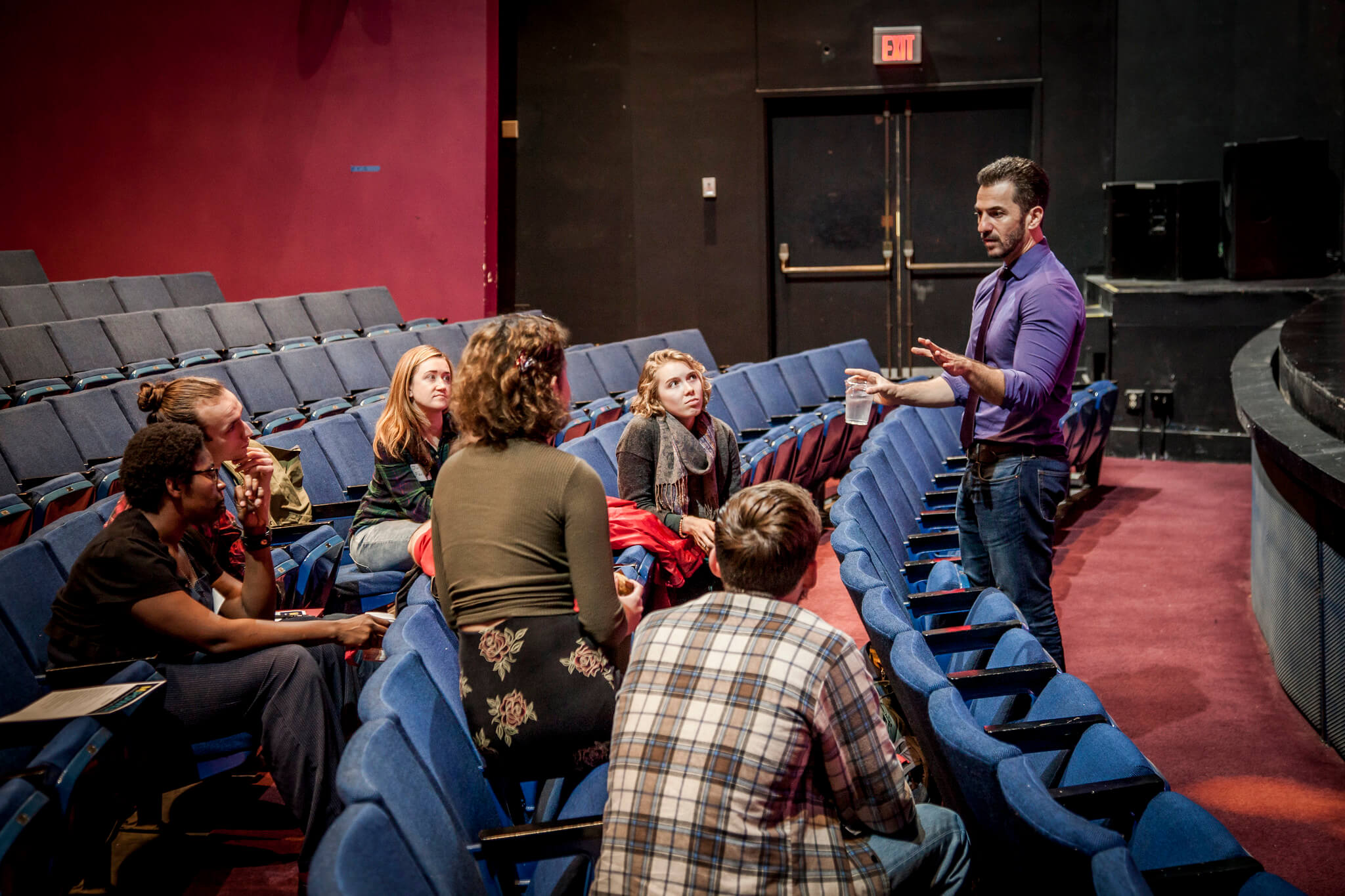 male teacher talks to students in an auditorium