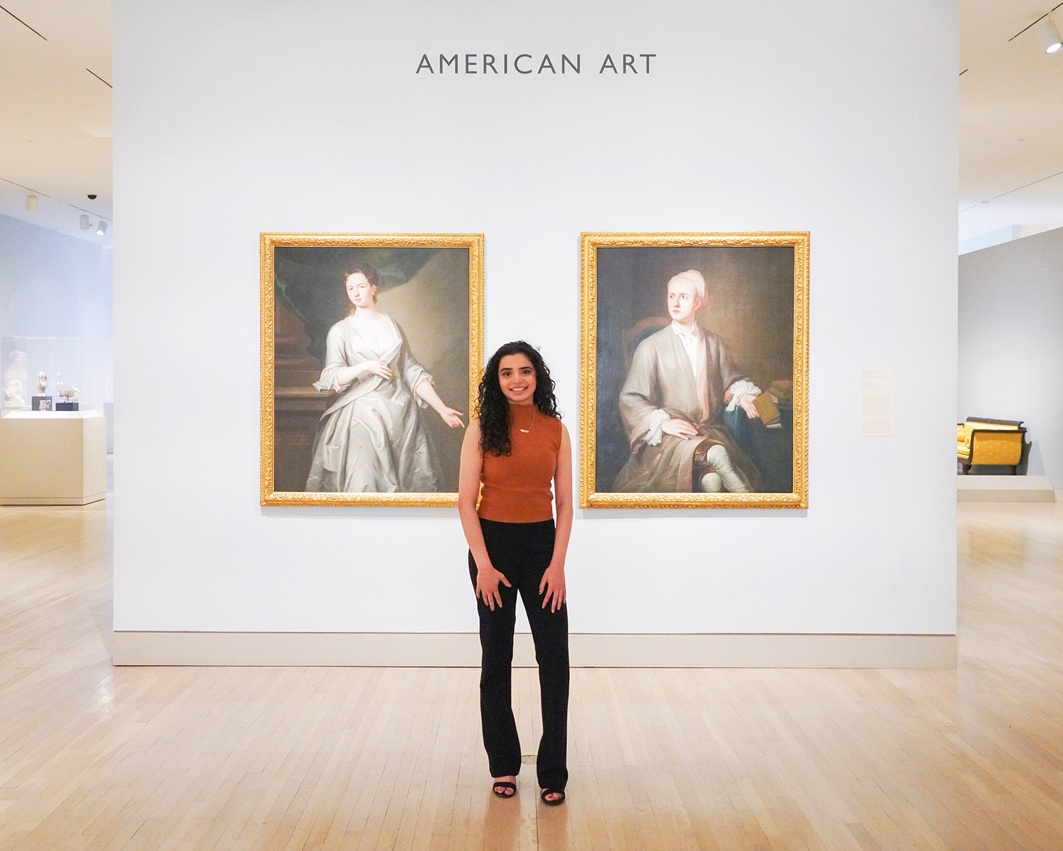 female student standing in front of two paintings