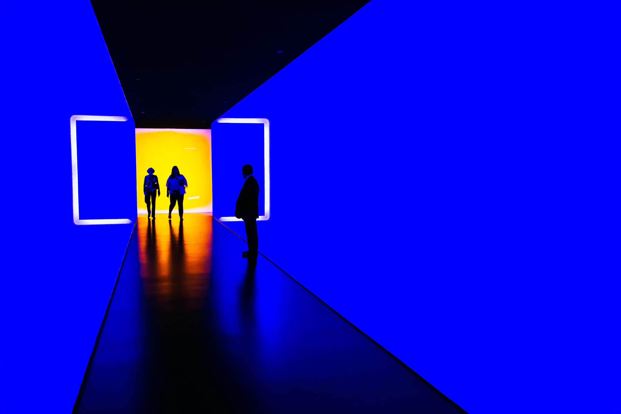 students silhouetted in a dark blue hallway