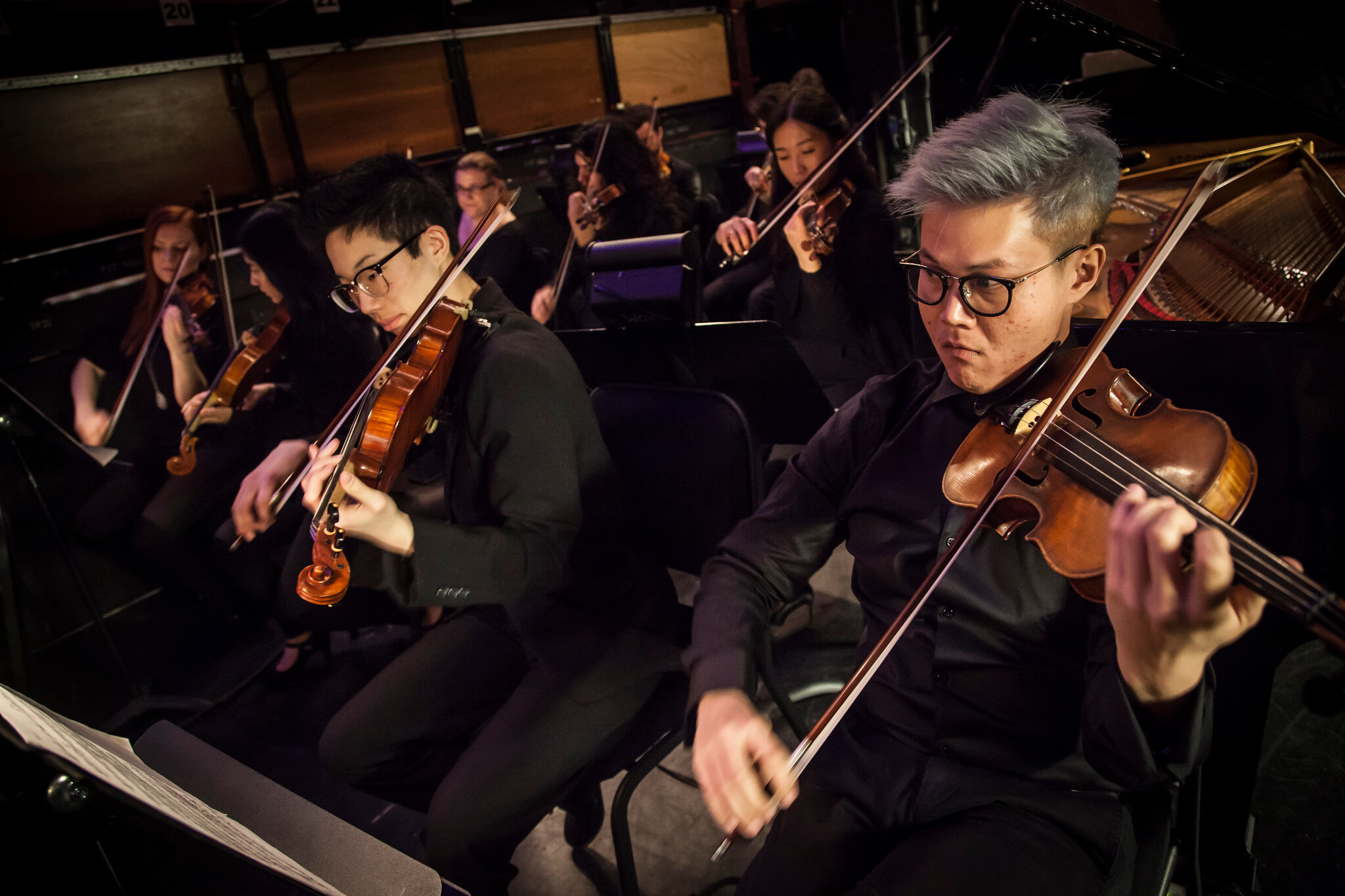 Two asian students playing violin in a pit orchestra at the Winspear Opera House