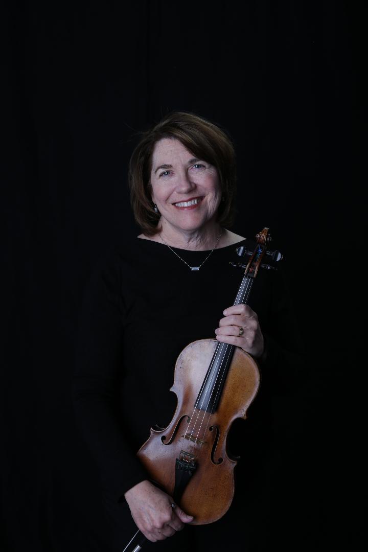 Susan Younghans holding a violin against a black background