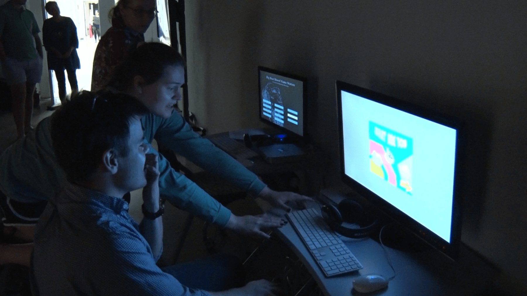 students work on a computer in a dark room