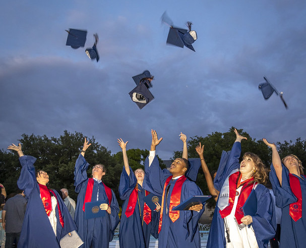 Meadows alumni throw their caps into the air at graduation.