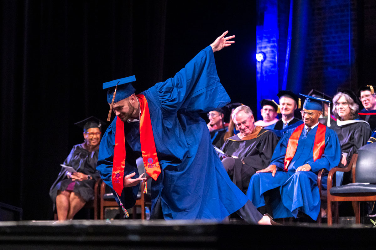 A graduate takes a bow after receiving their diploma at the 2023 Degree Recognition Ceremony.