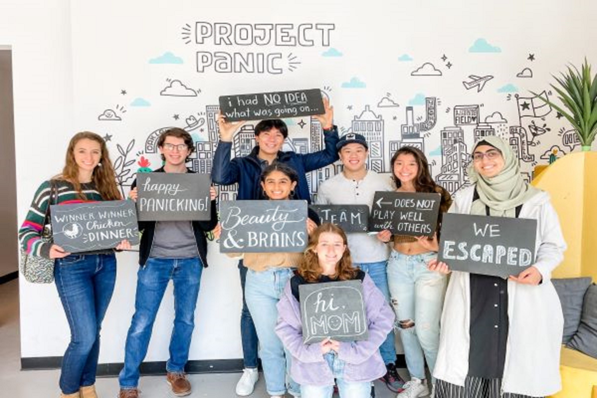 group of eight students posing with hand drawn signs