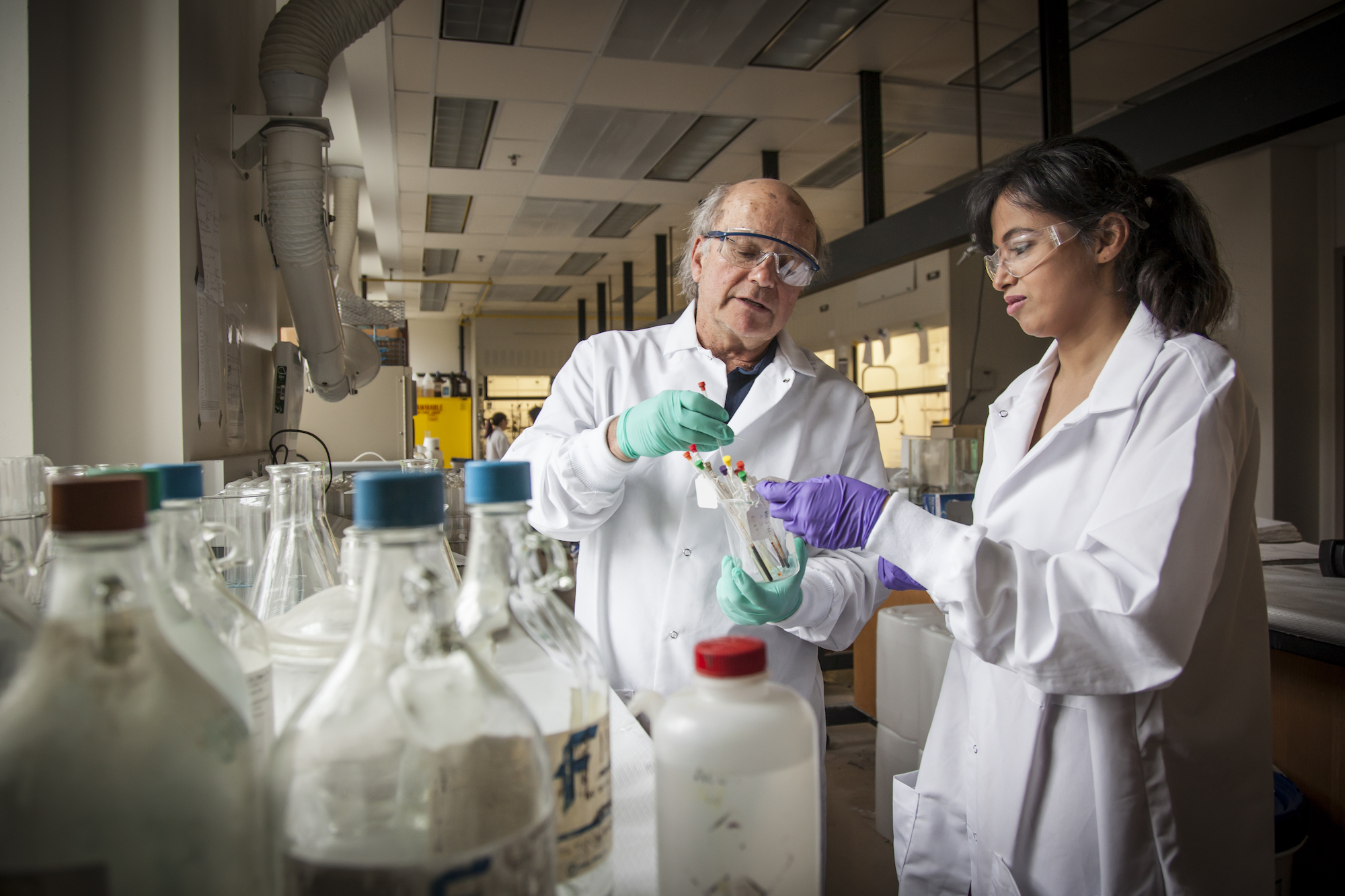 Dr. John Buynak demonstrating chemistry research technique with a student