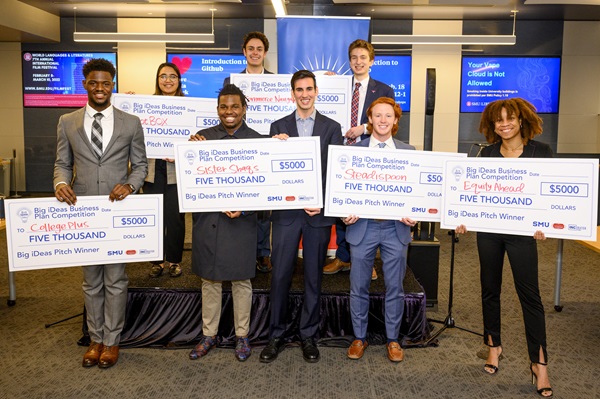 Student standing in a group holding their winning checks up